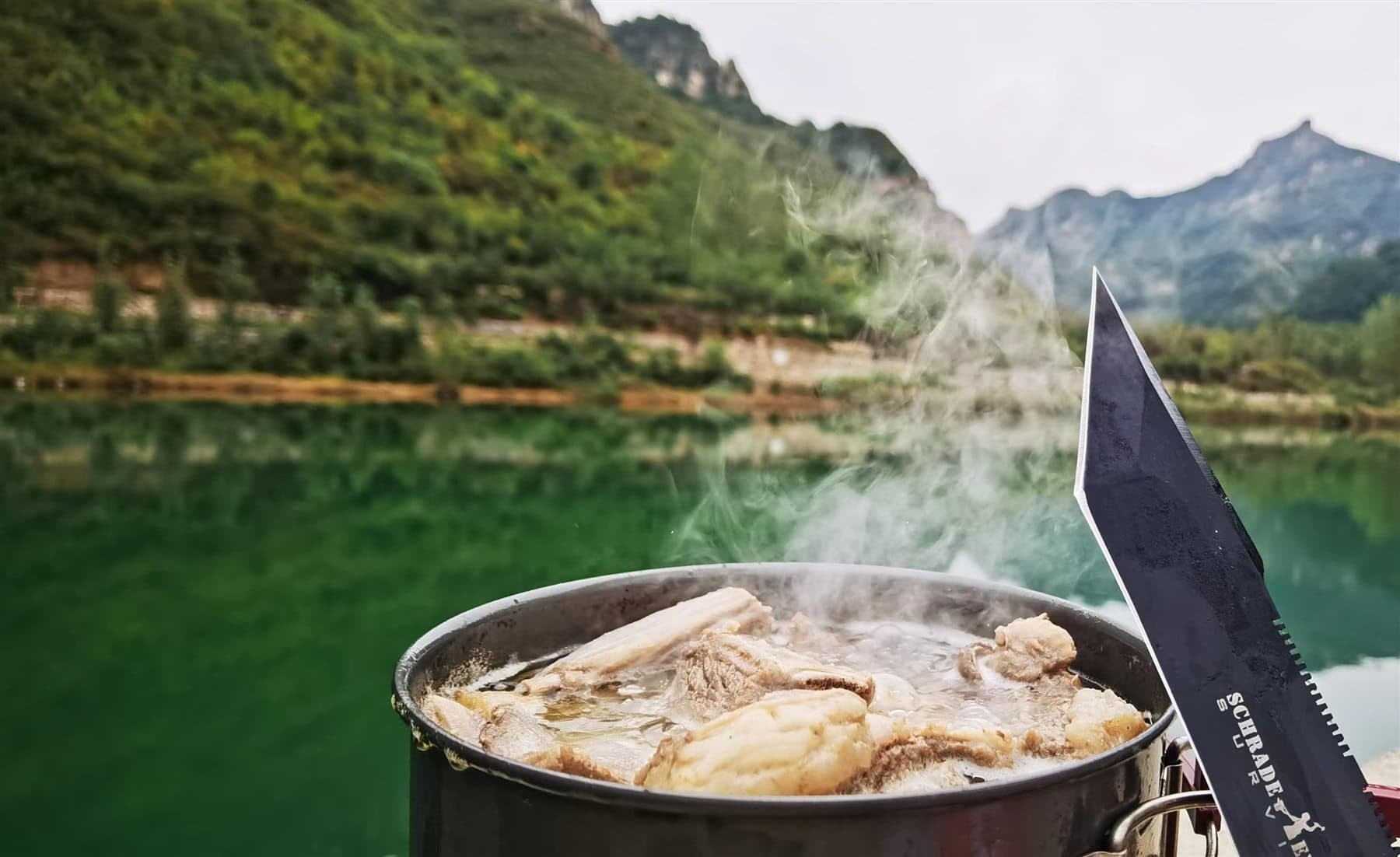 Outdoor hotpot beside a green mountain lake